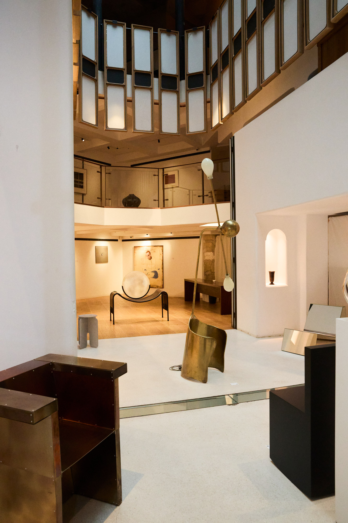 Art Rocker by Studio Goons, right, with a brass chair and a floor lamp at OGATA Paris.